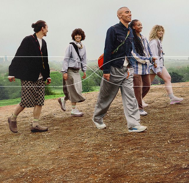 A group of people reach the top of a hill with a city skyline in the background.